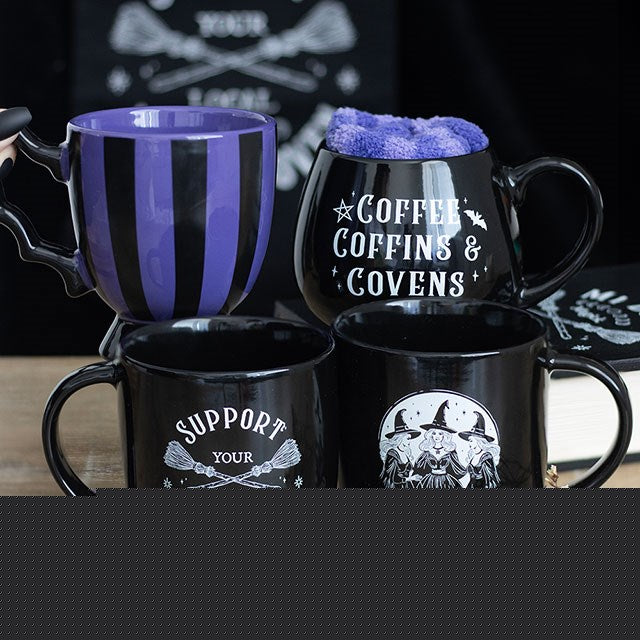 Set of black mugs with Halloween-themed designs on a wooden surface.