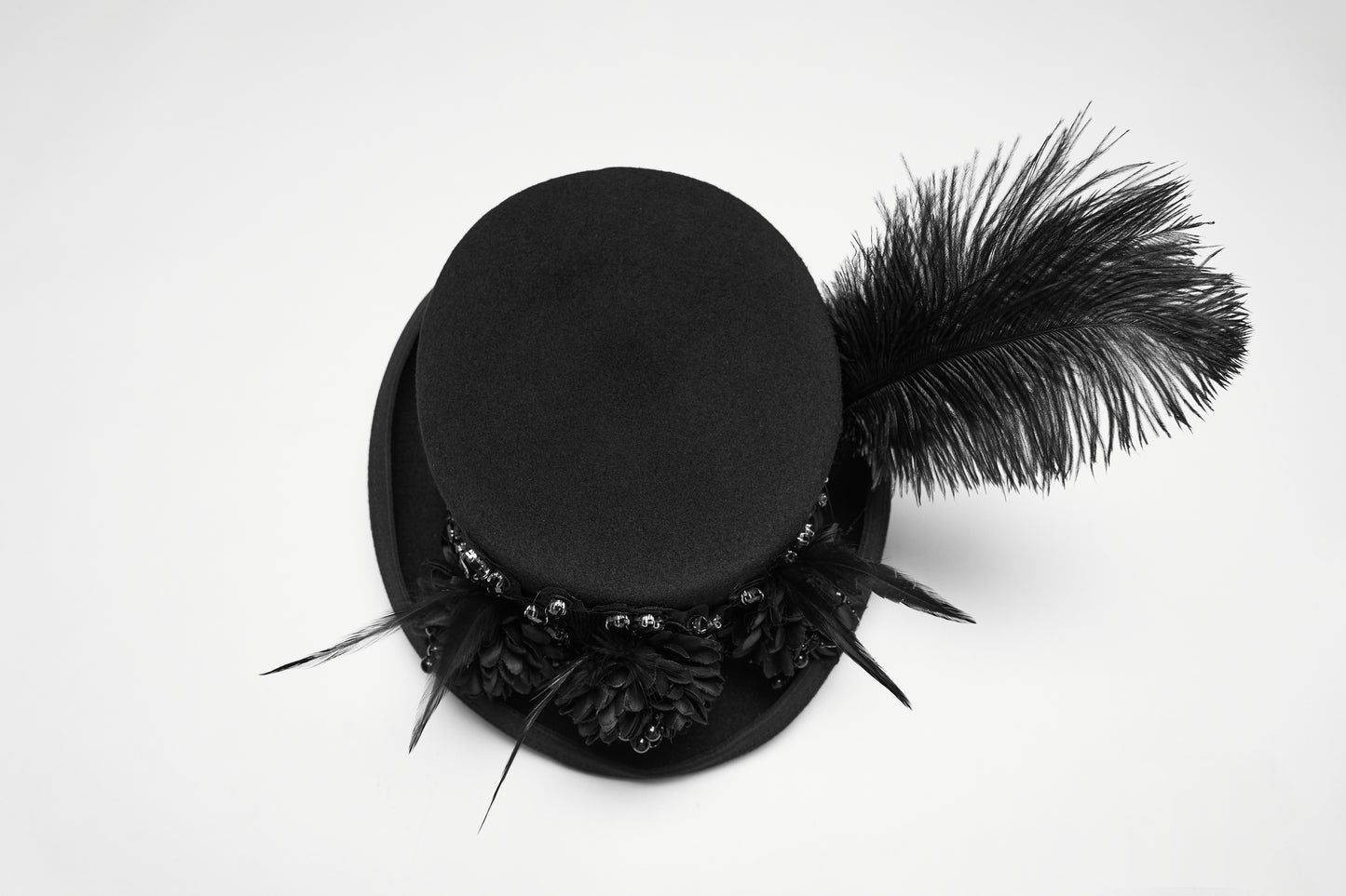 Goth feather formal hat with feather and floral embellishments, perfect for alternative fashion. Bold and dramatic styling.