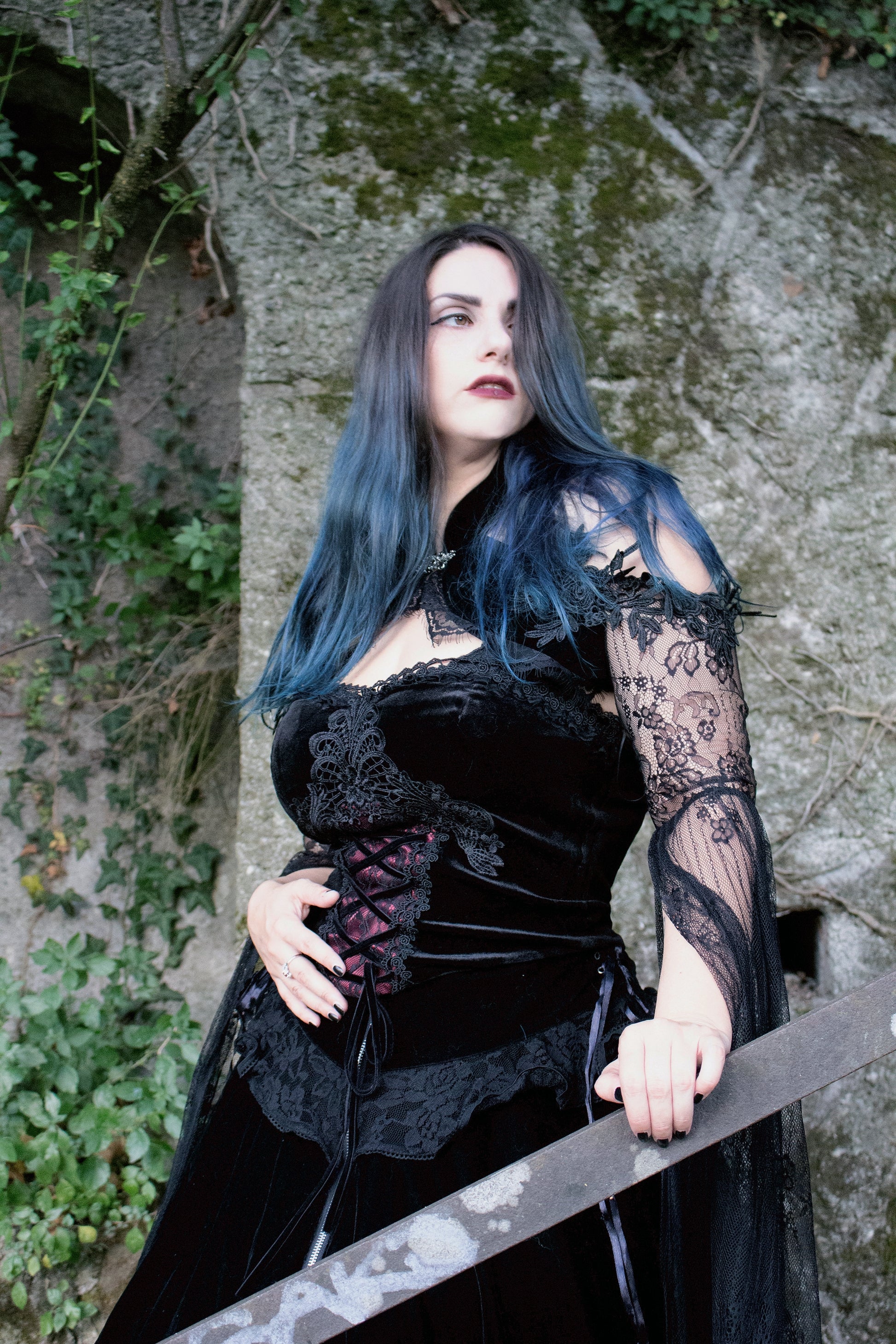 Angelineva_ wearing Dark in Love Gothic Velvet Corset Top stood against a stone wall