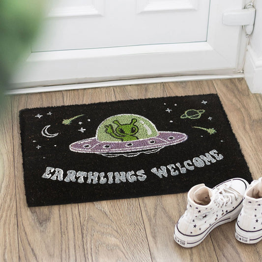 Alien Doormat featuring cheerful green alien in purple UFO with 'Earthlings Welcome' text, perfect for quirky home decor.