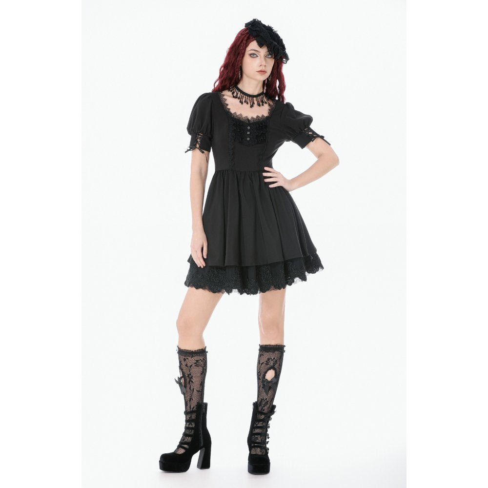 Woman wearing a black gothic dress with lace details on a white background