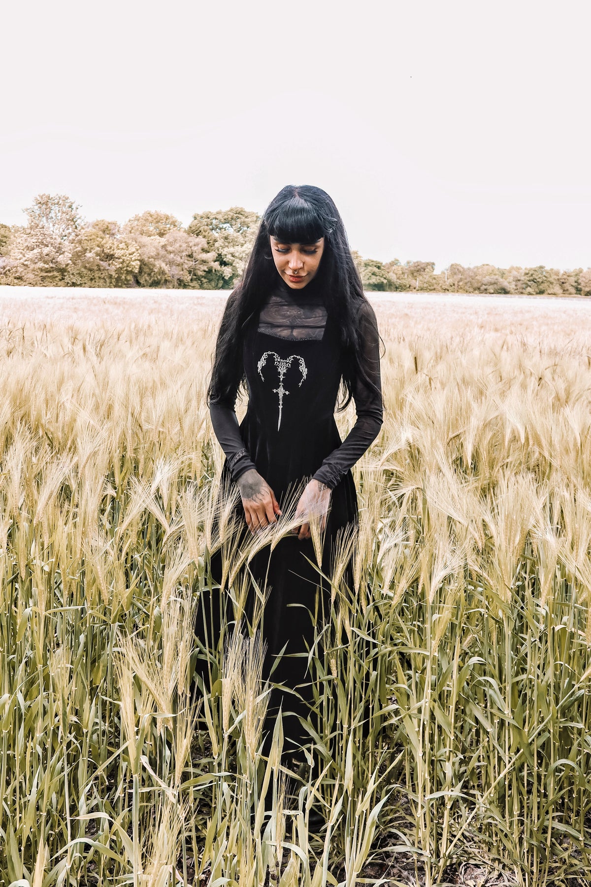 PJ the Heathen alternative model wearing a Dark in Love Gothic Velvet Maxi Dress styled over a long sleeve mesh top