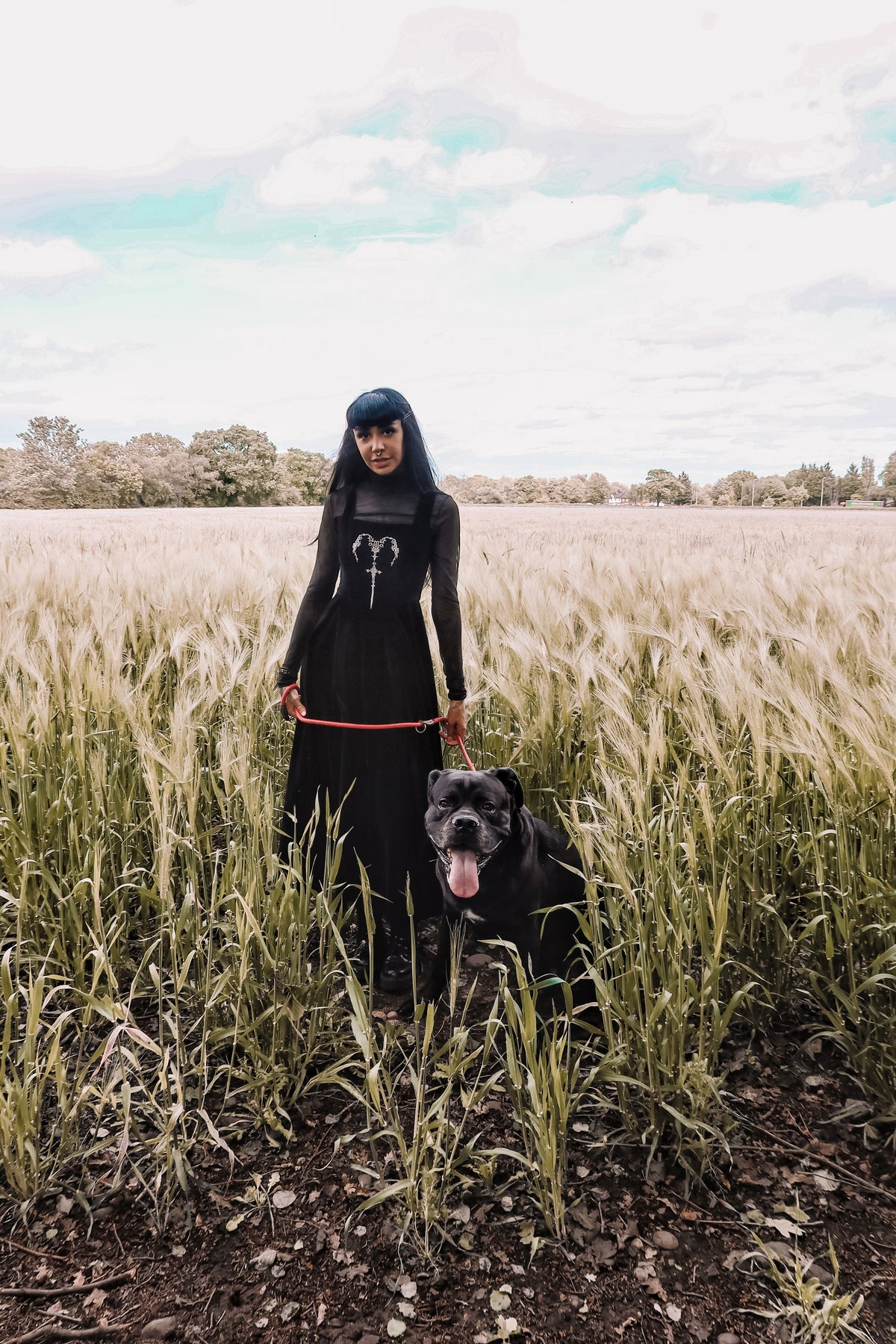 PJ the Heathen alternative model wearing a Dark in Love Gothic Velvet Maxi Dress stood with a large black hound