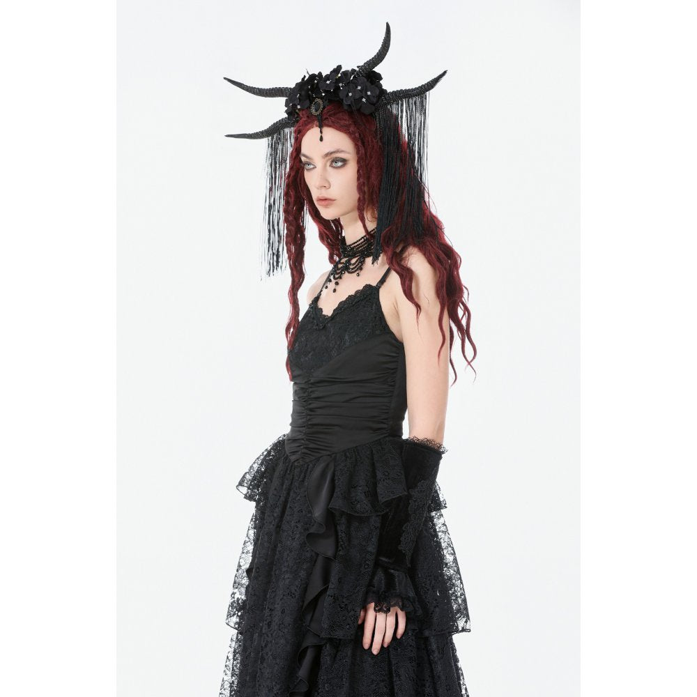Person wearing a black dress with ruffles and a headpiece with horns on a white background