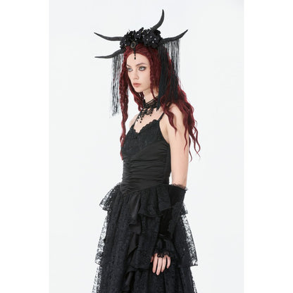Person wearing a black dress with ruffles and a headpiece with horns on a white background