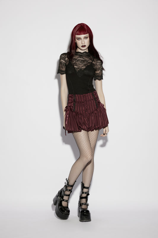 Model wearing a lace panel goth t shirt with a ruffled skirt and fishnet stockings, showcasing gothic style and elegance.
