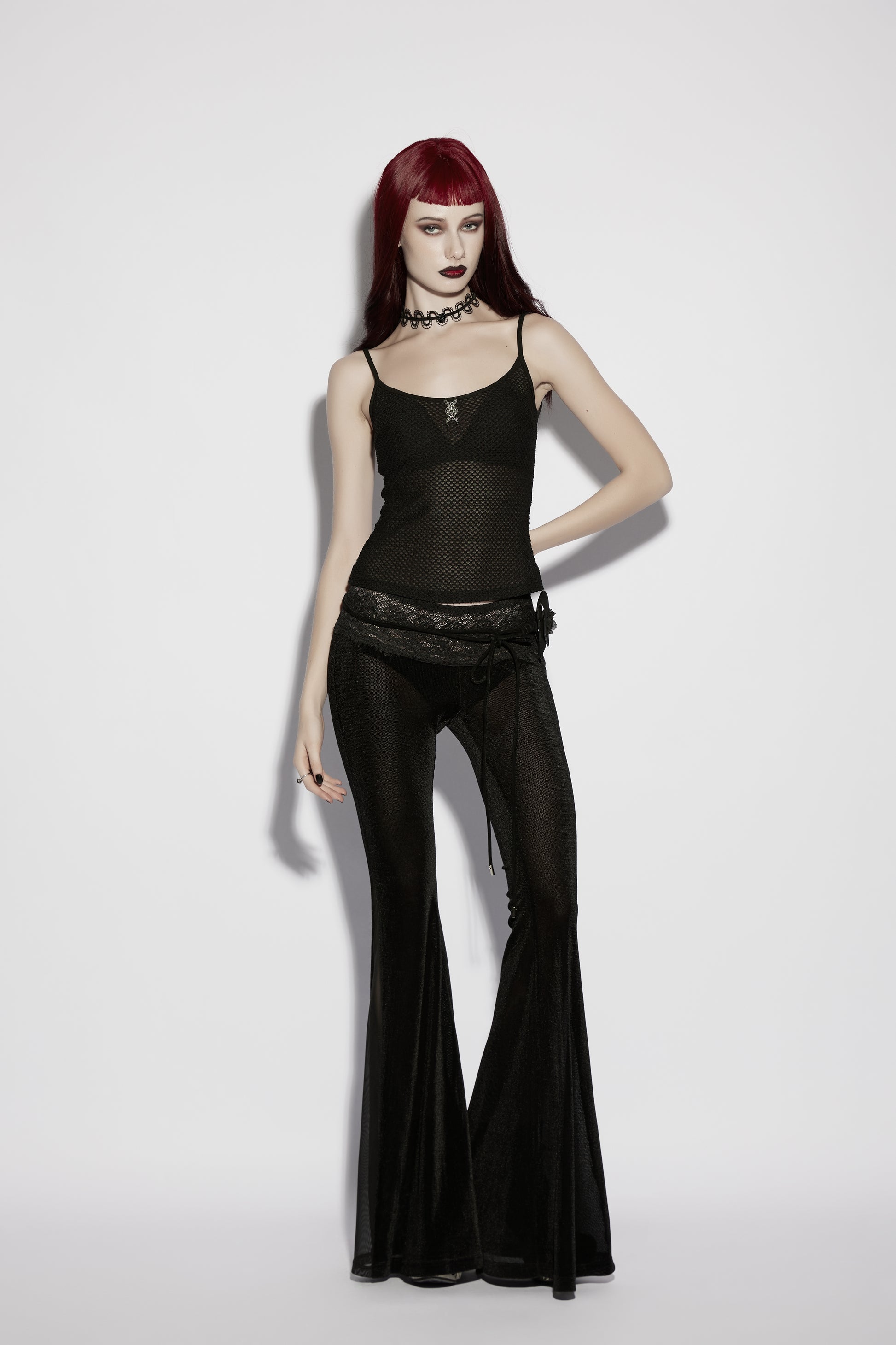 Model wearing a mesh goth camisole paired with flared black pants, showcasing a punk rave gothic style.