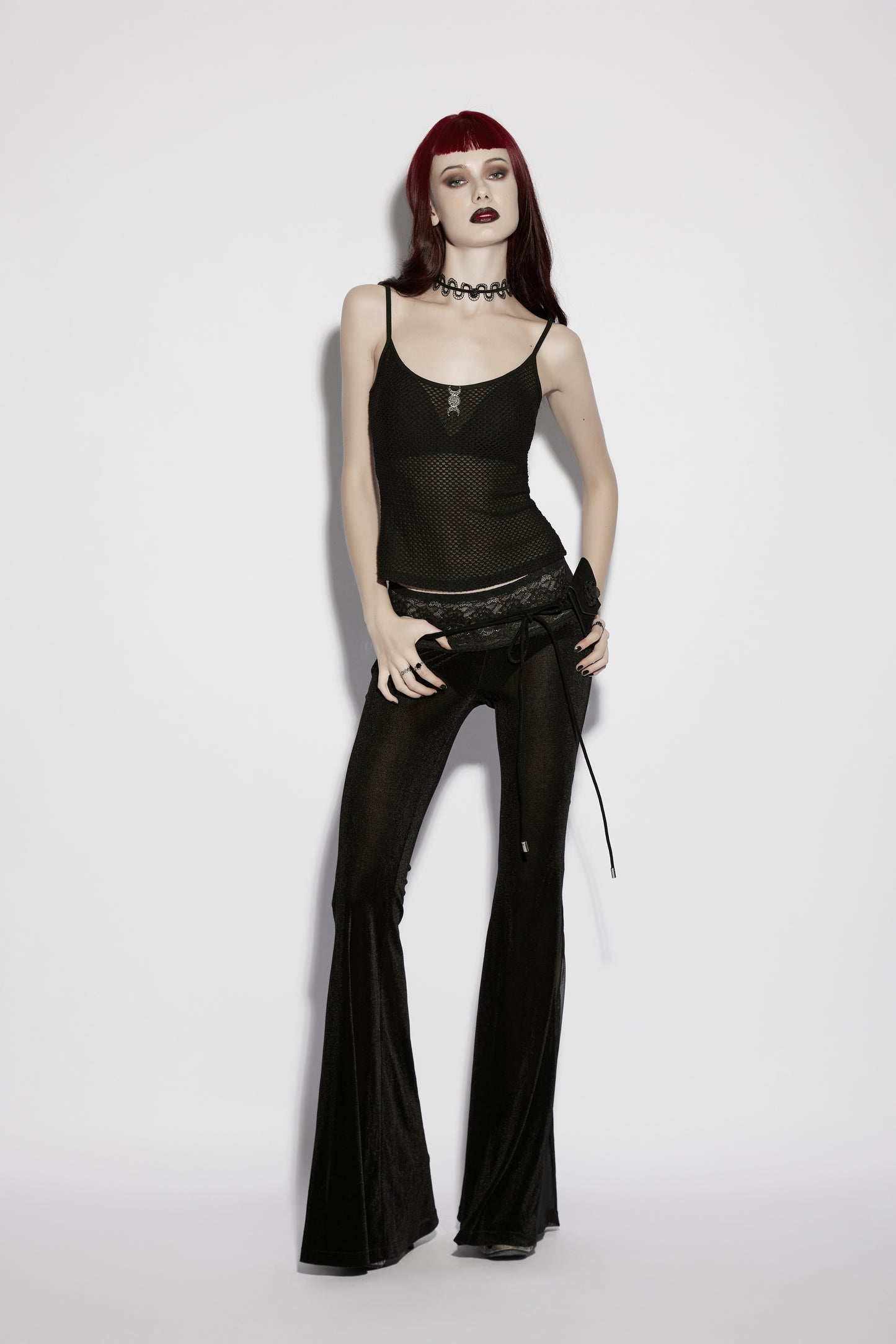 Model wearing a mesh goth camisole with dark flared pants, showcasing punk style and gothic fashion.