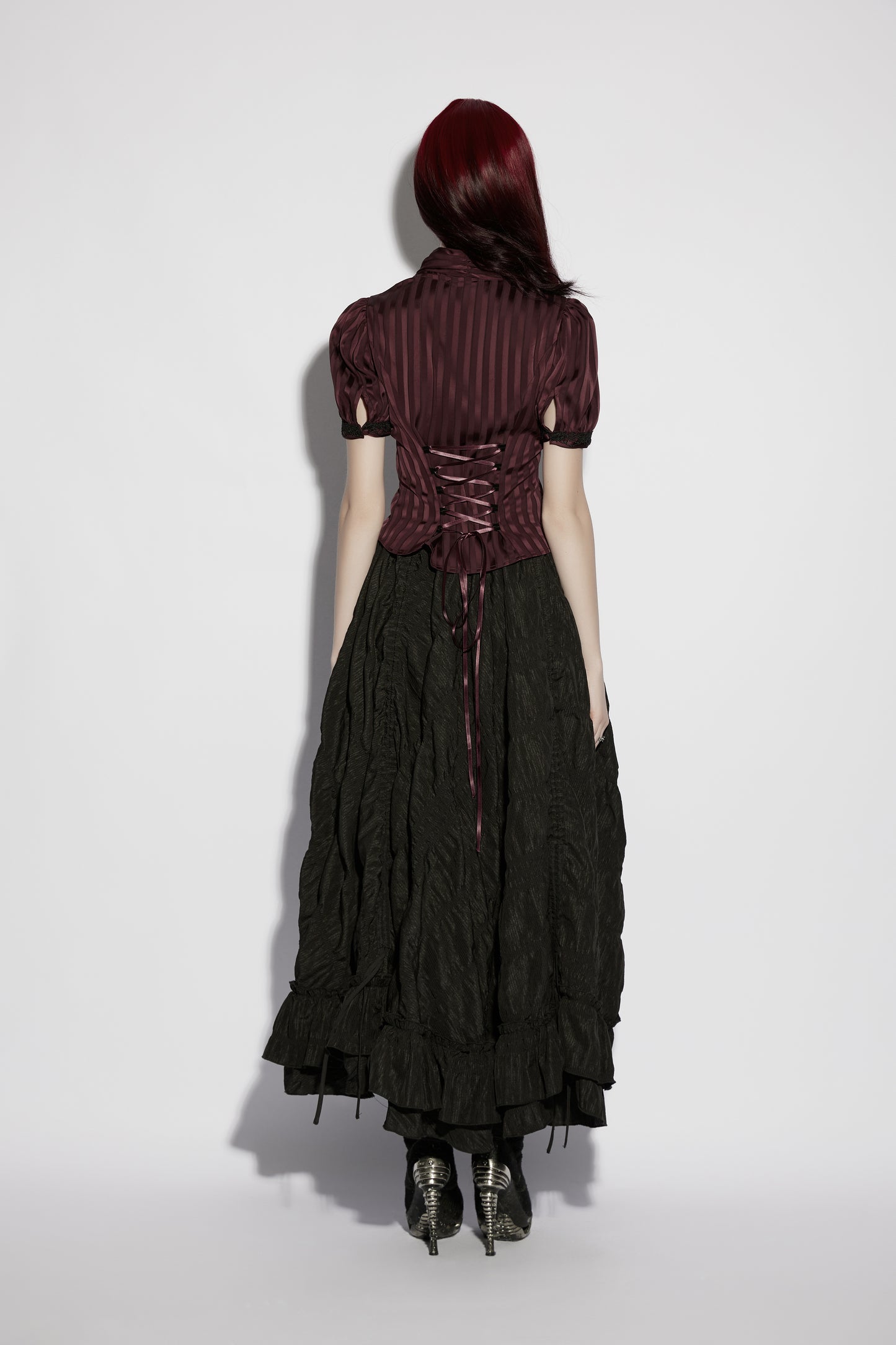 Back view of a model wearing the Punk Rave Morrigan Goth Pleated Retro Skirt paired with a dark striped top.