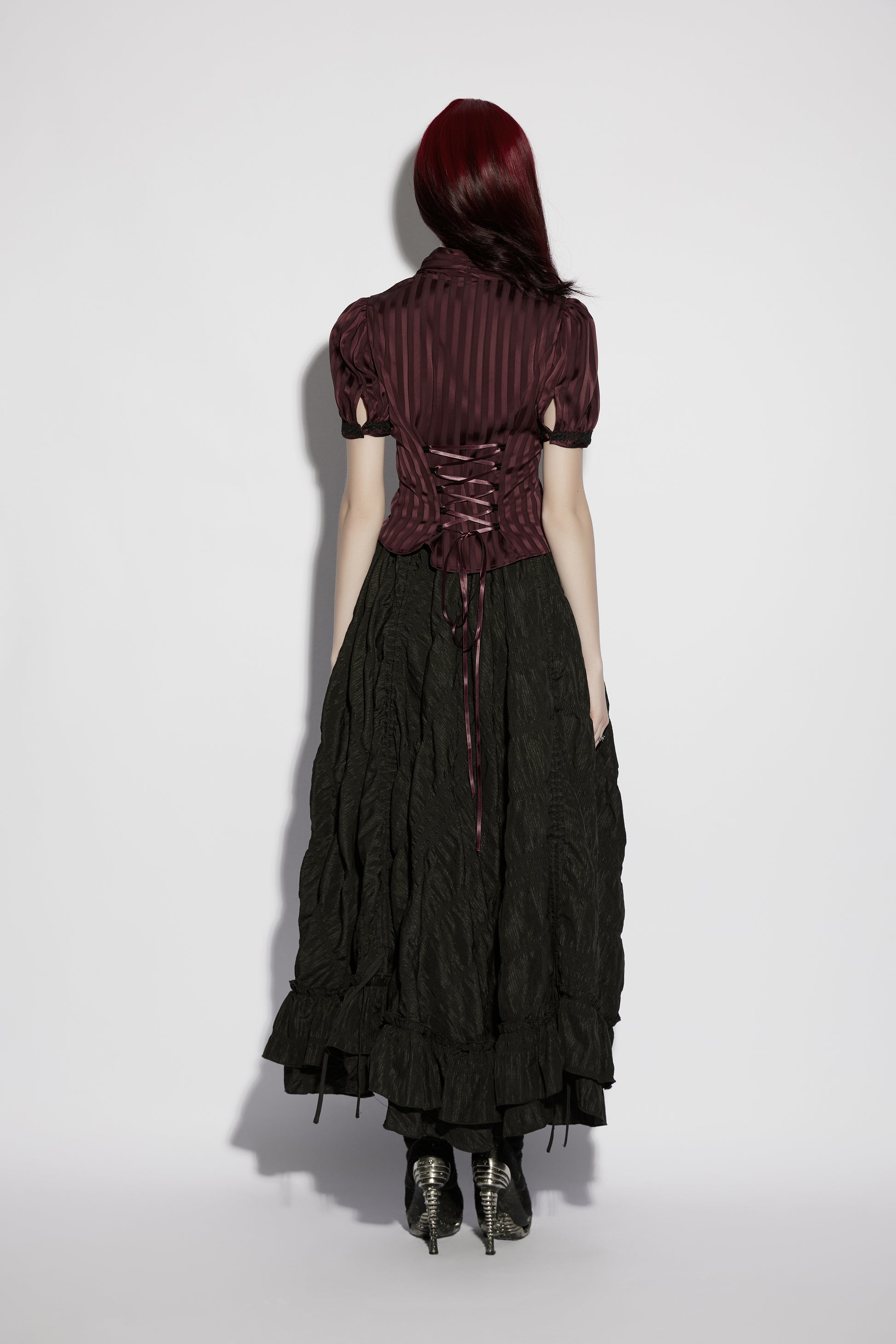Back view of a model wearing the Punk Rave Morrigan Goth Pleated Retro Skirt paired with a dark striped top.