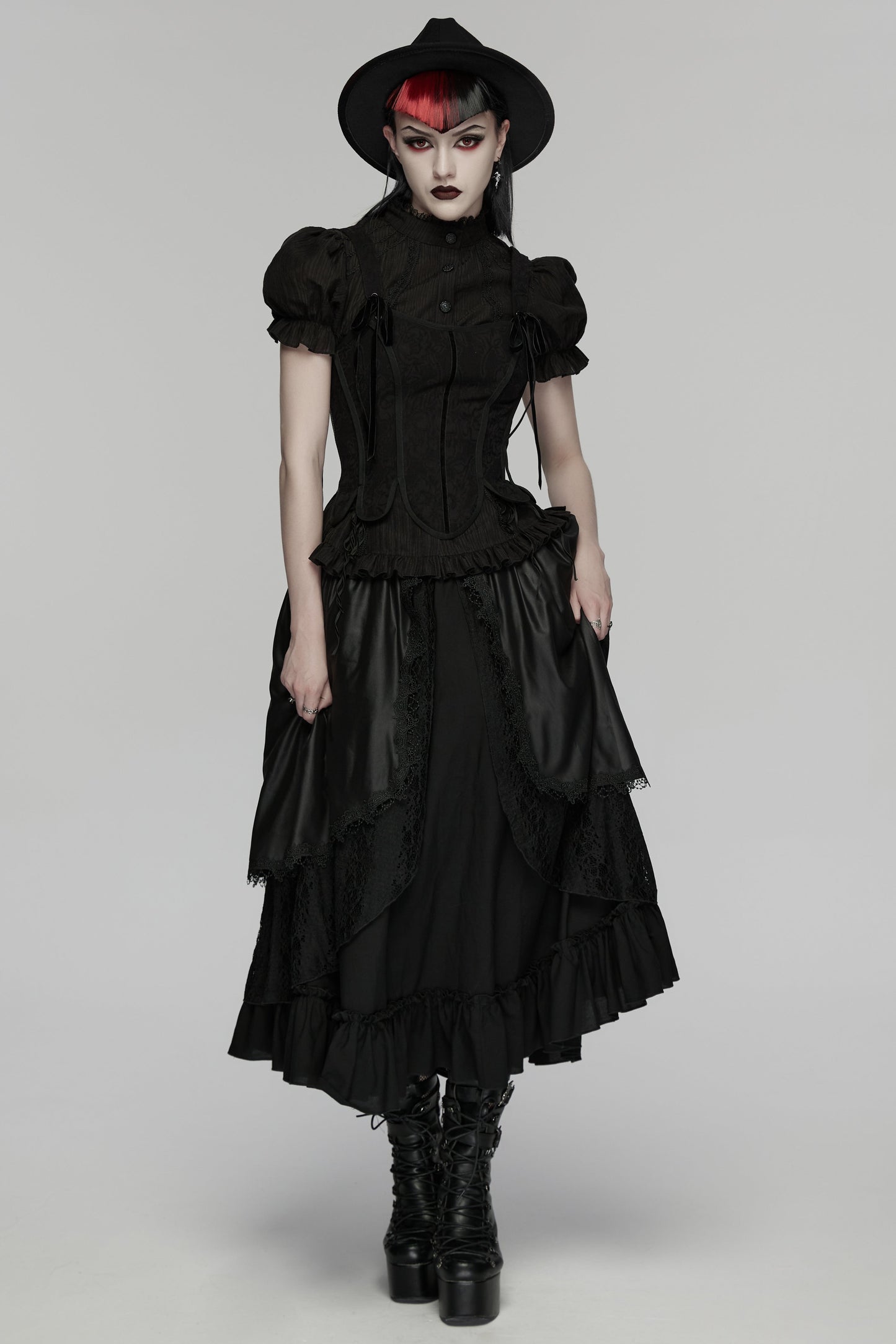 Model wearing a goth layered skirt with a dark romantic texture, complemented by a black hat and boots.