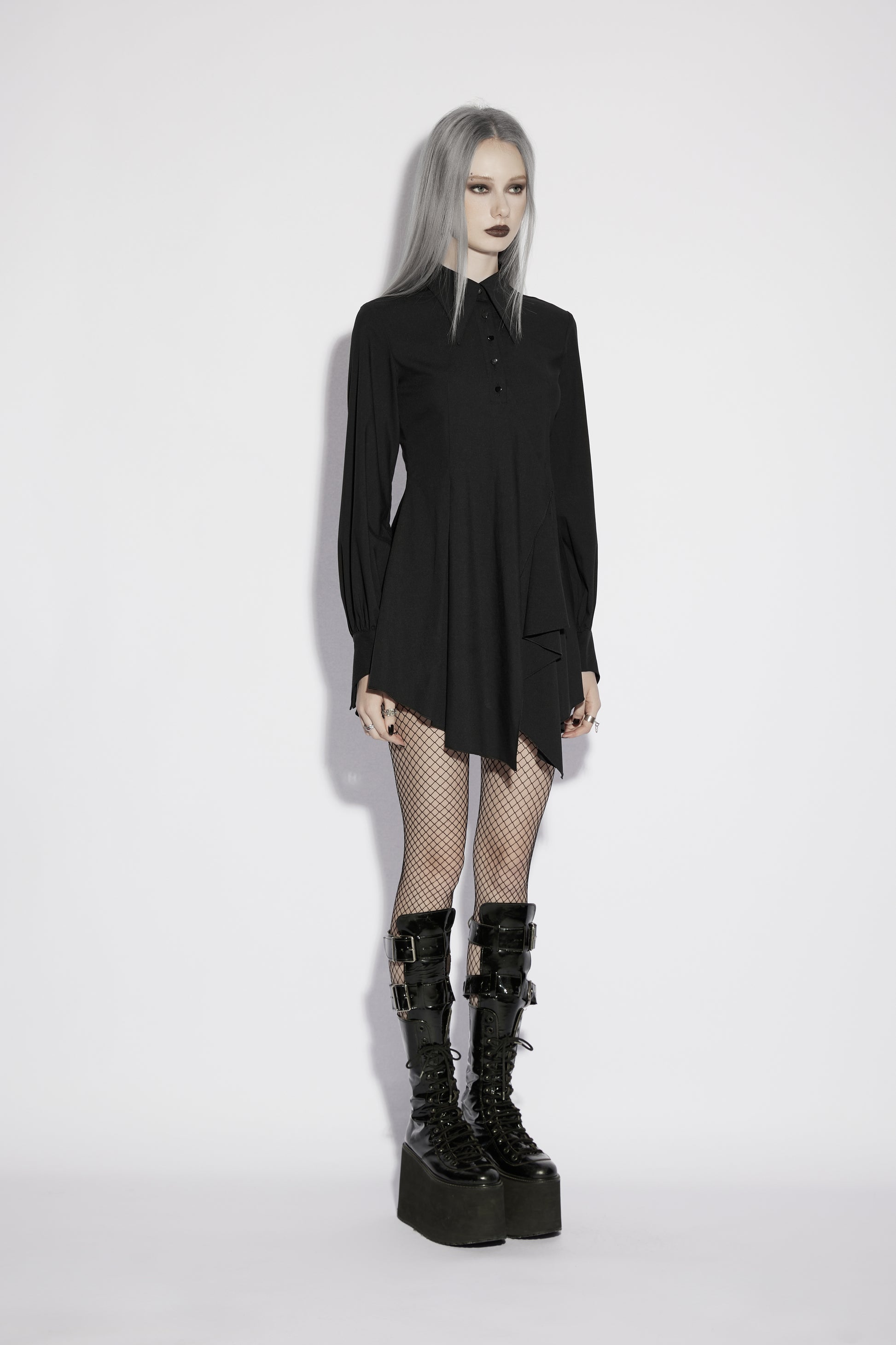 Model wearing Punk Rave Nyx Asymmetrical Shirt Dress with fishnet stockings and platform boots.
