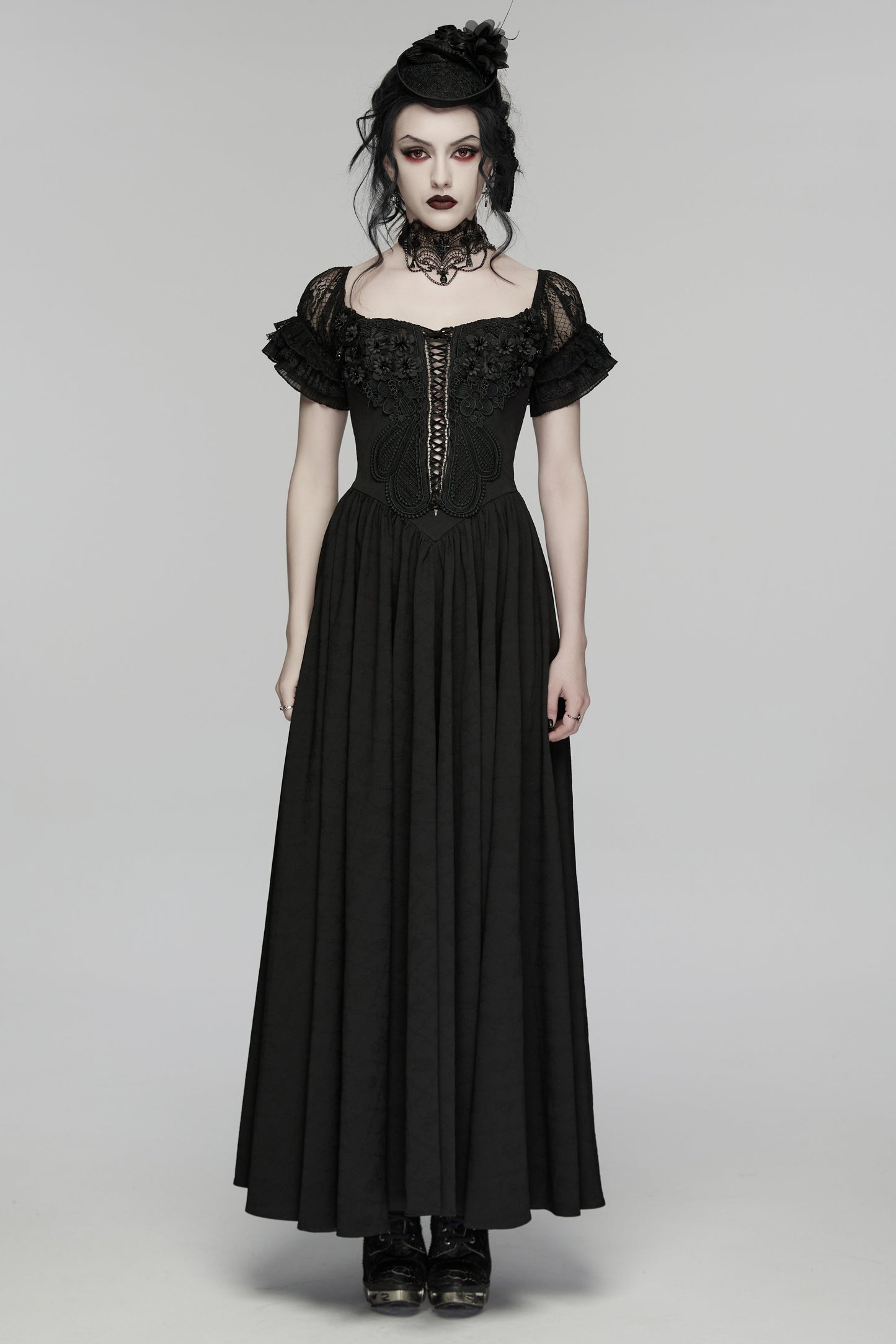 Woman wearing a black gothic-style dress on a gray background