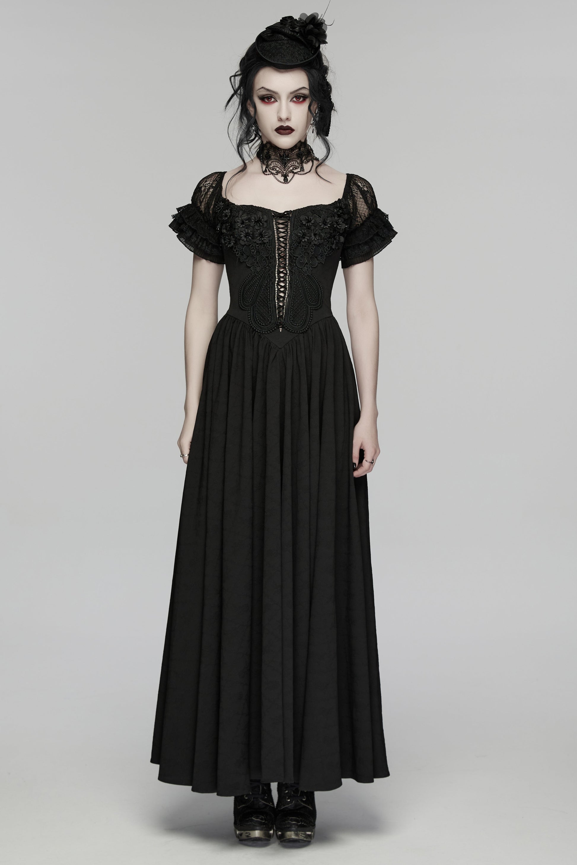 Woman wearing a black gothic-style dress on a gray background