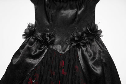 A close-up of a black satin and tulle dress with large fabric flowers at the waist and a sheer black underlayer showing red floral print.