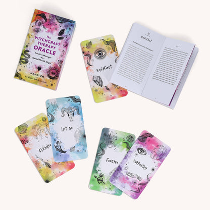 Oracle cards laid out on a pale pink background beside the open guidebook.