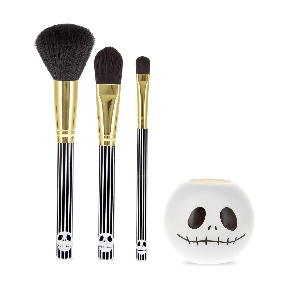 Makeup brushes laid out next to the Jack Skellington brush holder